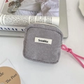 Detail view of grey corduroy makeup pouch with pink strap and metal zipper on white desk - Gray
