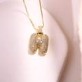 Gros plan du collier avec pendentif lettre H dorée et zircons scintillants - Lettre H