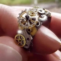 Vista macro dell'anello meccanico steampunk con ingranaggi di orologio a strati e metallo bicolore - US 7 / AJZ1957 Oro