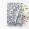 Light grey cashmere-feel scarf with blue floral print and fringe detail laid on white - White Base Blue Orchid