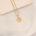 Detailed macro view of a gold initial G pendant with honeycomb texture on box chain - Letter G