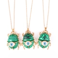 Detailed view of beetle-shaped green malachite pendants with blue evil eye charms - Synthetic Watermelon Stone (No Chain)