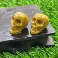Gelbe Totenkopf-Miniaturen aus Naturstein auf Holzsockel über grünem Grashintergrund - Goldener Quarz