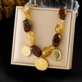 Maillard kralenketting met gouden hangers gepresenteerd op een beige sieradendoosje - Ketting (N4008)