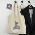 Detail van de crèmekleurige canvas tas met een zak voorzien van houndstooth beerprint - Geruite Beer