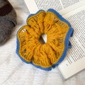 Detailed close-up of a dual-layer crochet flower scrunchie on a vintage book - Hollow Color Block Style / Yellow