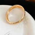 Dettaglio ravvicinato di un bracciale dorato martellato con chiusura a cerniera - Stile con Texture Trapuntata / Oro
