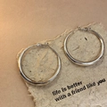 Macro shot of silver twisted geometric hoop earrings on a vintage paper with text - Medium Silver Classic Hoop Style (51#)