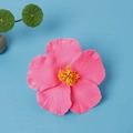 Pink hibiscus hair clip made of EVA foam on a blue background for beach vacations - Pink