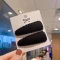Detalle de las pinzas para el cabello en terciopelo negro con pompones en tarjeta blanca - Negro