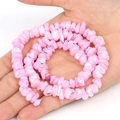 Gros plan de perles de nacre roses irrégulières dans une main pour bijoux DIY - Rose Irrégulier