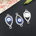 Silver Evil Eye charms with blue enamel and sparkling crystals on a textured surface - Bright Silver Evil Eye 13x25mm