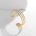Dettaglio del bracciale a strati in oro con finitura martellata artigianale e design aperto - Oro