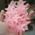 Hand holding several pink star-shaped glow in the dark plastic wall stickers for decor - 100 Pieces / 3.8cm/Glow / Pink