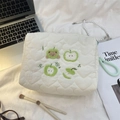 Close-up of cream quilted cosmetic bag with green apple embroidery and heart stitching - Green Apple