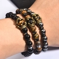 Dettaglio di tre bracciali in ossidiana e occhio di tigre con ciondoli corona in bronzo - Set 3 Pezzi Occhio di Tigre Ematite Opaca