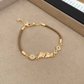 Detailed macro view of a gold koi carp and copper coin bracelet with brown cord - 1# Brown Woven Bracelet - Gold Koi and Coin Elements