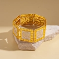 Detail of vintage gold textured bracelet with white accents on stone display stand - White