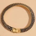 Detailopname van een vergulde armband met drie rijen zwarte zirkonia steentjes van bovenaf - Zwart