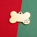 Dettaglio di medaglietta dorata a forma di osso con zampa in strass su fondo colorato - 24X36MM / Placcato Oro 18K