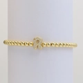 Detail of gold beaded elastic bracelet featuring a sparkling zircon micro-pave letter R charm - Letter R