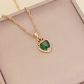 Detalle de collar dorado con colgante de corazón verde y corona sobre joyero de color beige - Verde (4#)