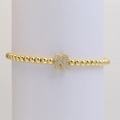 Macro view of gold beaded bracelet with zircon pave letter N charm on white stand - Letter N