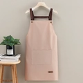 Pink waterproof kitchen apron with neck strap and large front pocket on wood hanger - Leather Label Pink