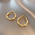Detailed top view of twisted golden hoop earrings on elegant champagne silk fabric - Gold Twisted Round Hoop Jewelry (E035)