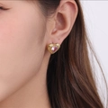 Close-up of heart-shaped gold earring with a pink gemstone center worn by a model - Pink
