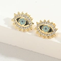 Detail view of gold Evil Eye stud earrings featuring white zircons and blue enamel inlay - Black Eye Style