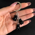 Detail of three black resin gummy bear charms on a polished silver metal keychain ring - Black