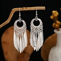 Detail view of silver bohemian tassel earrings hanging on a natural wooden branch - Silver Bohemian Ring Leaf Tassel Style (E2873-1)
