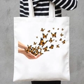 White canvas tote bag with orange butterflies print held by a model in casual stripes - Hands & Butterflies (STD707-Q)