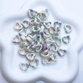 Macro shot of ink-painted heart ceramic beads in a white floral dish for DIY jewelry - Purple & Green Ink Wash