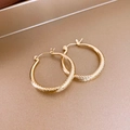 Vista detallada de pendientes de aro dorados con textura acanalada y diseño de metal torcido - Pequeño / Dorado