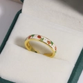 Detail of gold enamel ring with white red and green flower patterns on velvet - White