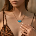 Golden necklace with semi-circular turquoise stone pendant worn by model outdoors - 18K Gold