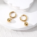Macro detail of golden irregular oval hoop earrings with spherical pendant on white blocks - 8# Gold Bead Pendant
