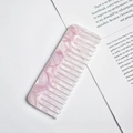 Detail of pink marble pattern wide-tooth acetate comb placed on an open book page - Lavender Marble