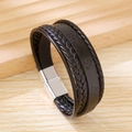 Close-up of a black braided leather bracelet featuring a silver anchor embossed strap - Black