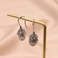 Baroque grey pearl earrings on silver hooks displayed on a gold stand with fabric - Gray Freshwater Pearl