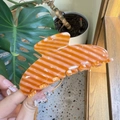 Close-up of a large orange and white striped acetate hair claw clip held by hand - Large / Blood Orange Stripes