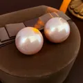 Elegante runde rosa Perlenohrstecker mit Metallglanz auf brauner Samtschmuckschatulle - Rosa