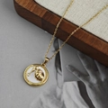 Gros plan détaillé d'un collier doré avec médaillon en nacre sur un plateau en bois - Collier Pendentif Coquillage Rond - Blanc