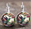 Gros plan de boucles d'oreilles cabochon en verre avec colibri et fleurs sur pierre - Style 2