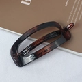 Elegant tortoiseshell rectangular hollow hair clip placed on a white textured background - Coffee Tortoise Shell