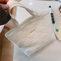 Dettaglio della borsa trapuntata bianca con ricamo a conchiglia e etichetta simple wish - Ricamo a Conchiglia