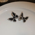 Detailaufnahme von silbernen Schmetterlingsohrringen mit schwarzer Emaille auf Teller - Schmetterling Ohrstecker (925 Silber Nadel/Schwarz)