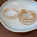 Detailed view of assorted gold open bangles with floral and star motifs on a ceramic plate - 8# Bracelet (HB4527)